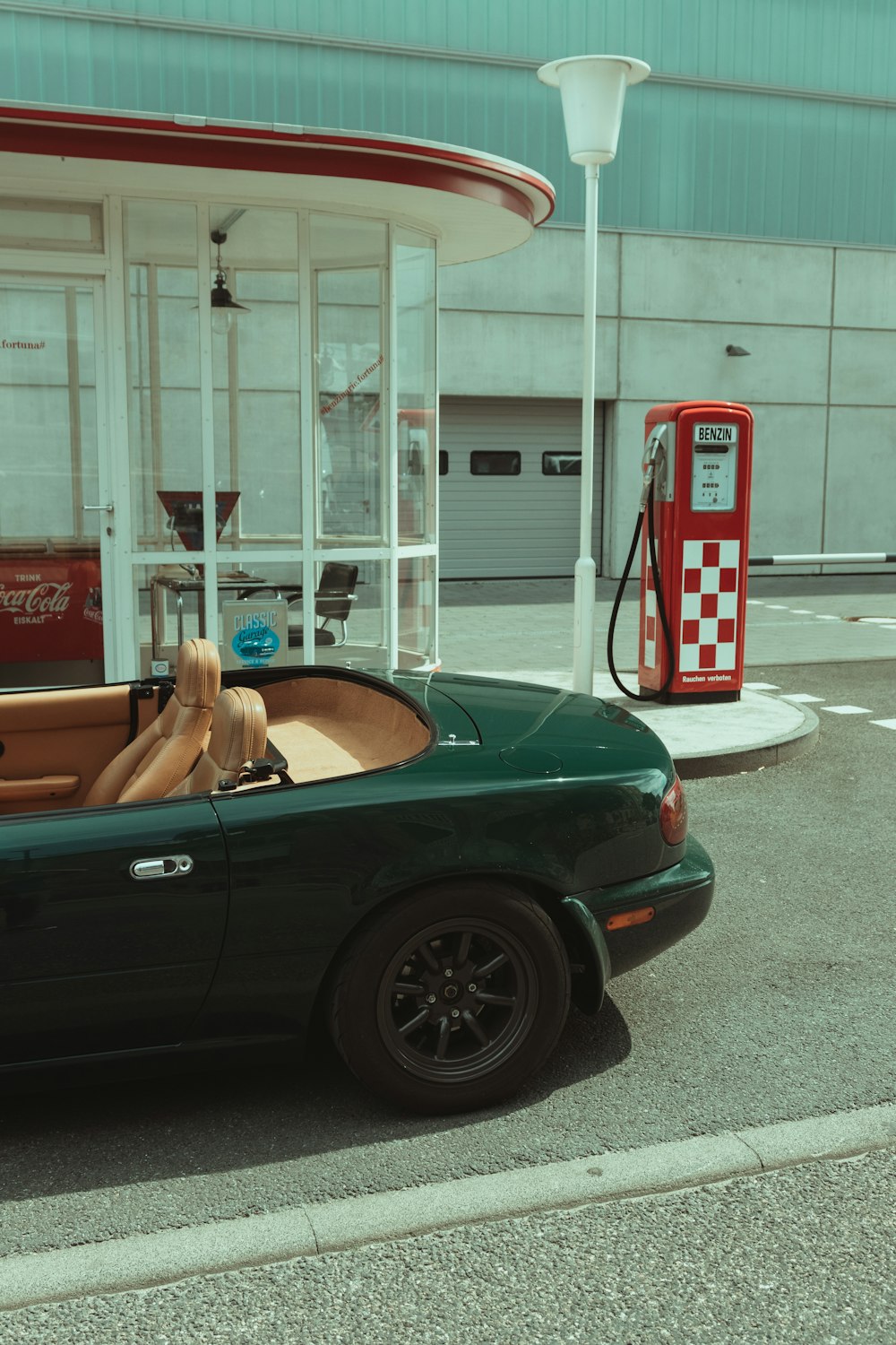 a green car parked in front of a gas station