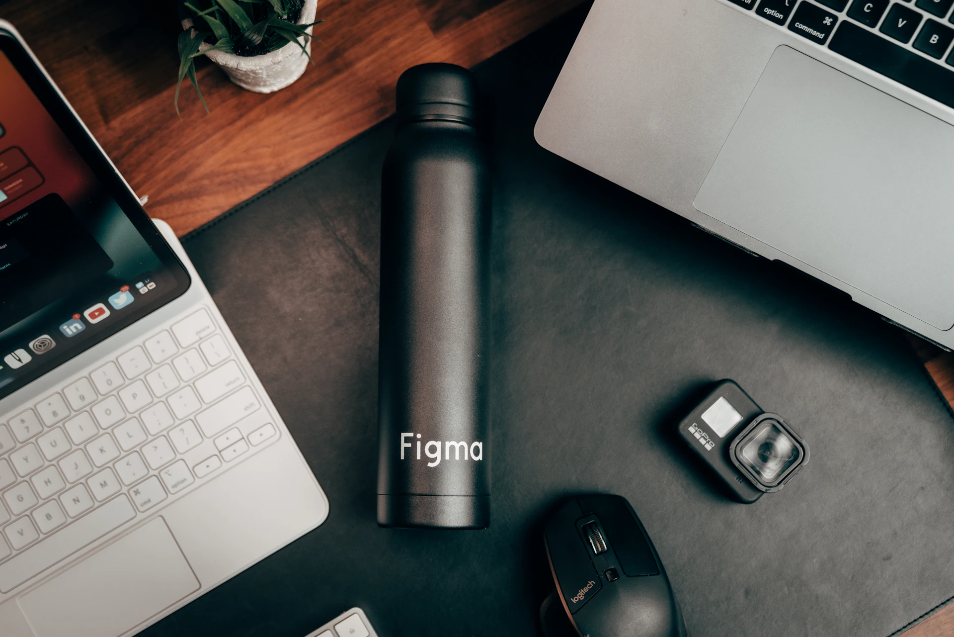 a laptop, camera, cell phone, and a water bottle on a desk