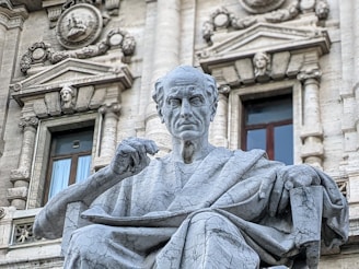 a statue of a man sitting in front of a building