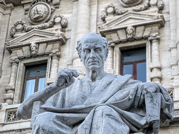 a statue of a man sitting in front of a building