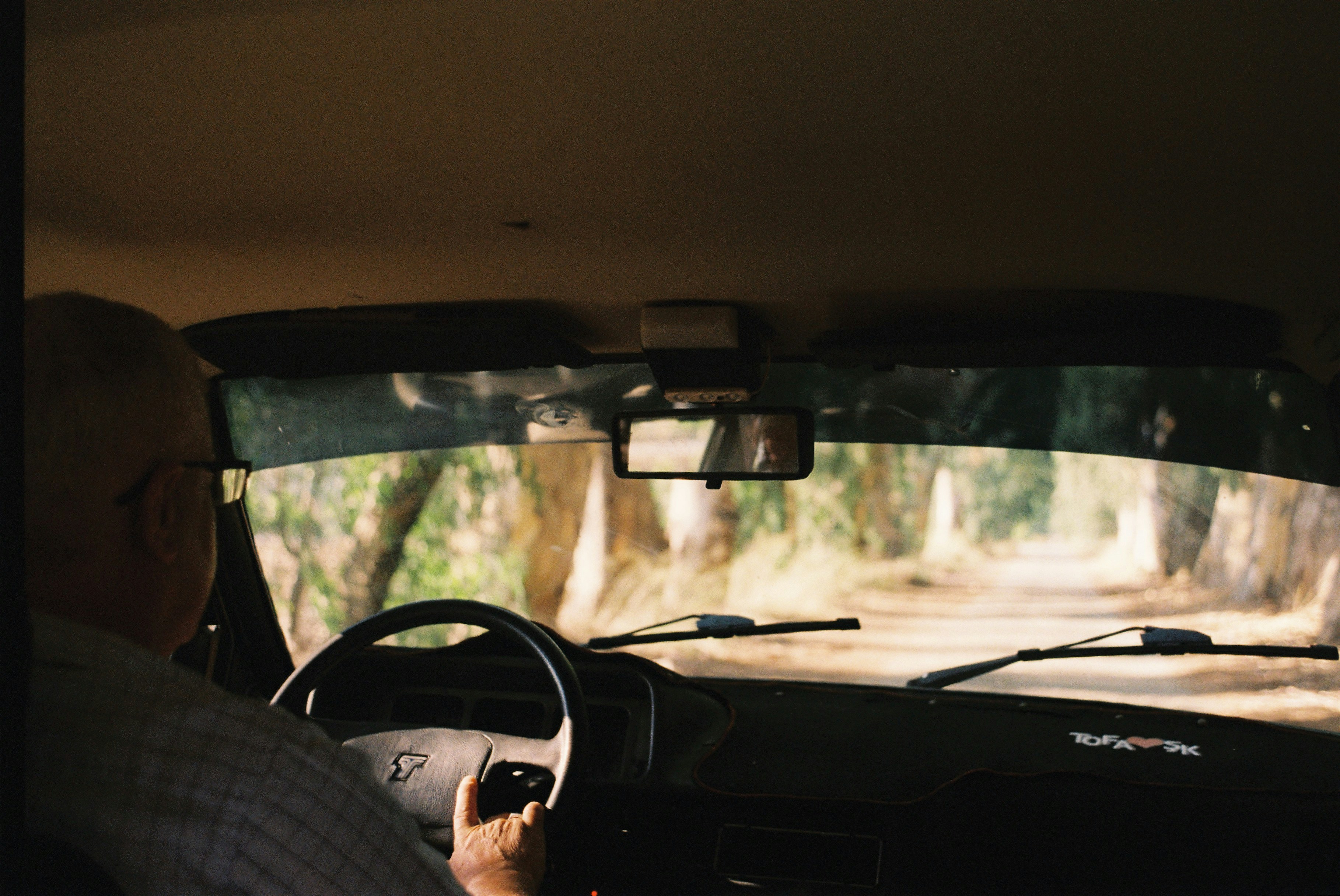 a man driving a car down a dirt road