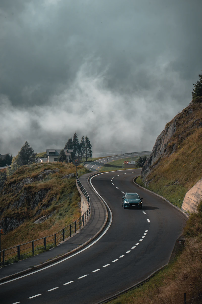 Car driving down a winding road under cloudy skies