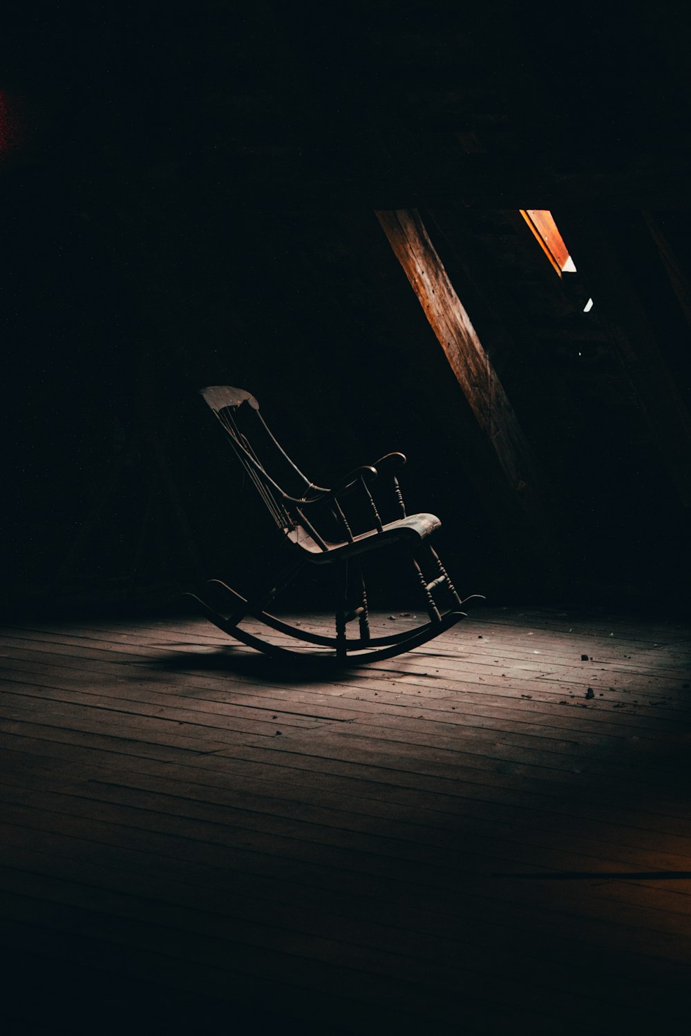 a rocking chair on a wooden floor in a dark room