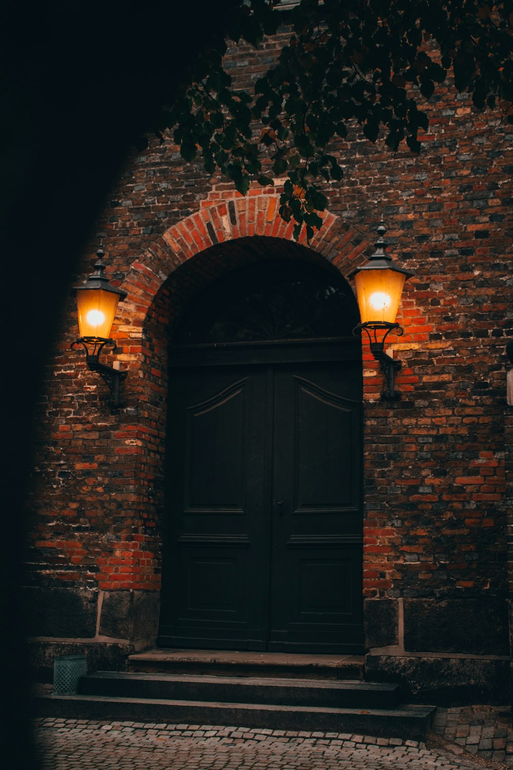 a brick building with a black door and two lights