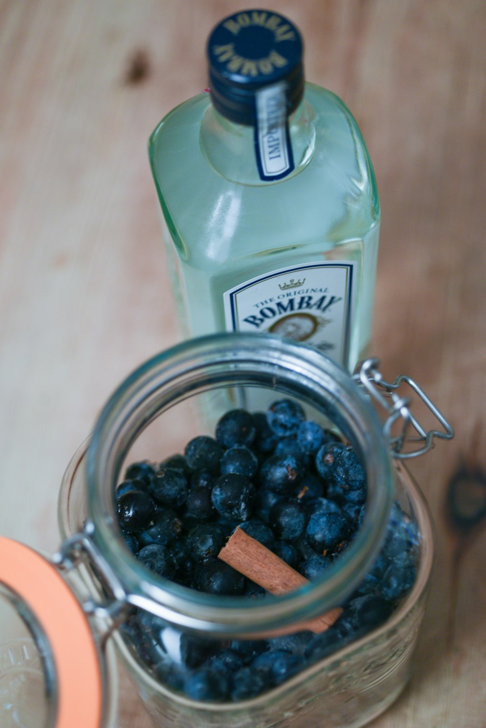 a glass jar filled with blueberries next to a bottle of gin