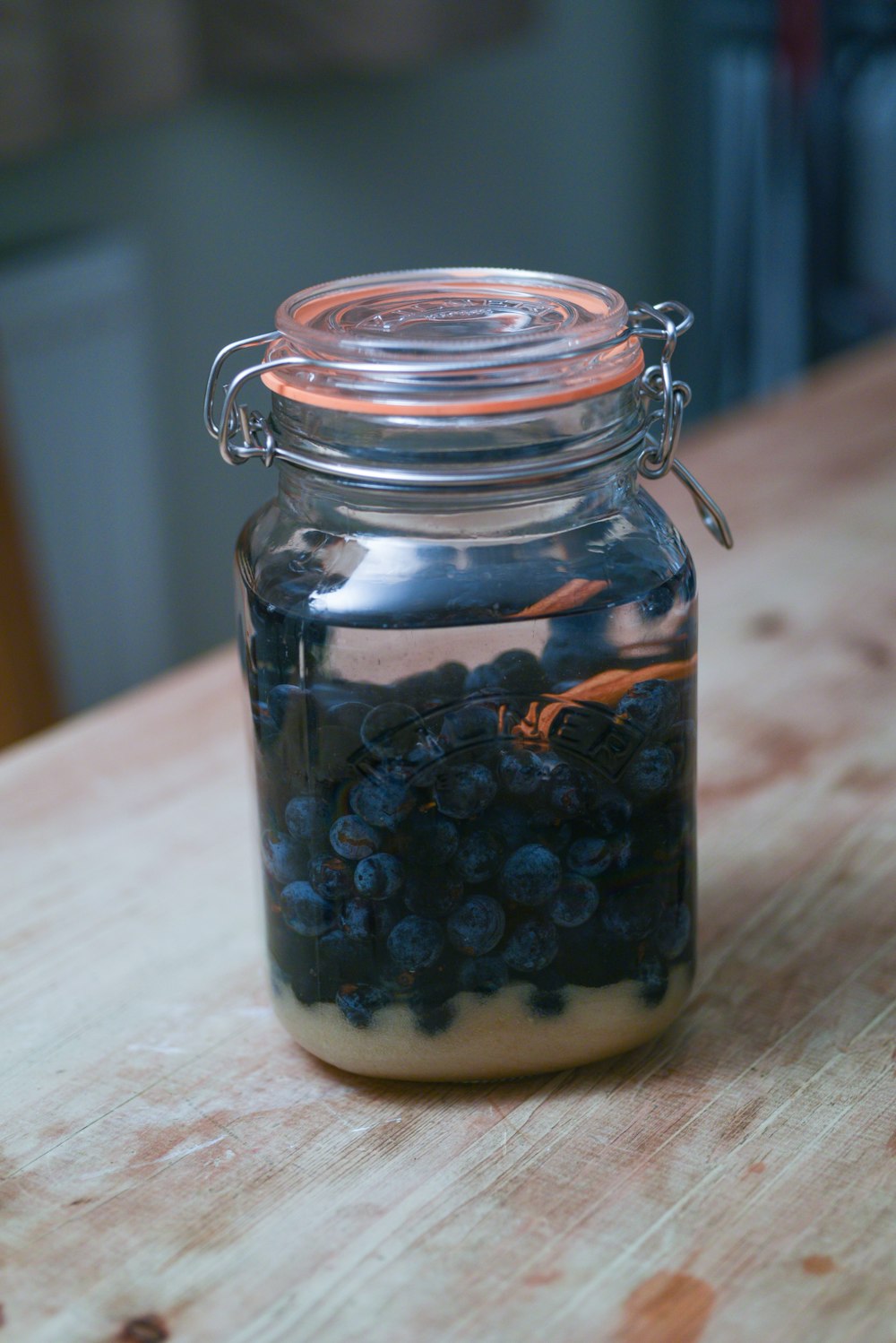 a glass jar filled with blueberries sitting on top of a wooden table