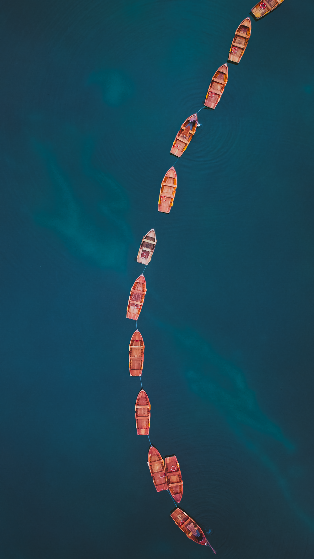 a long line of boats floating on top of a body of water