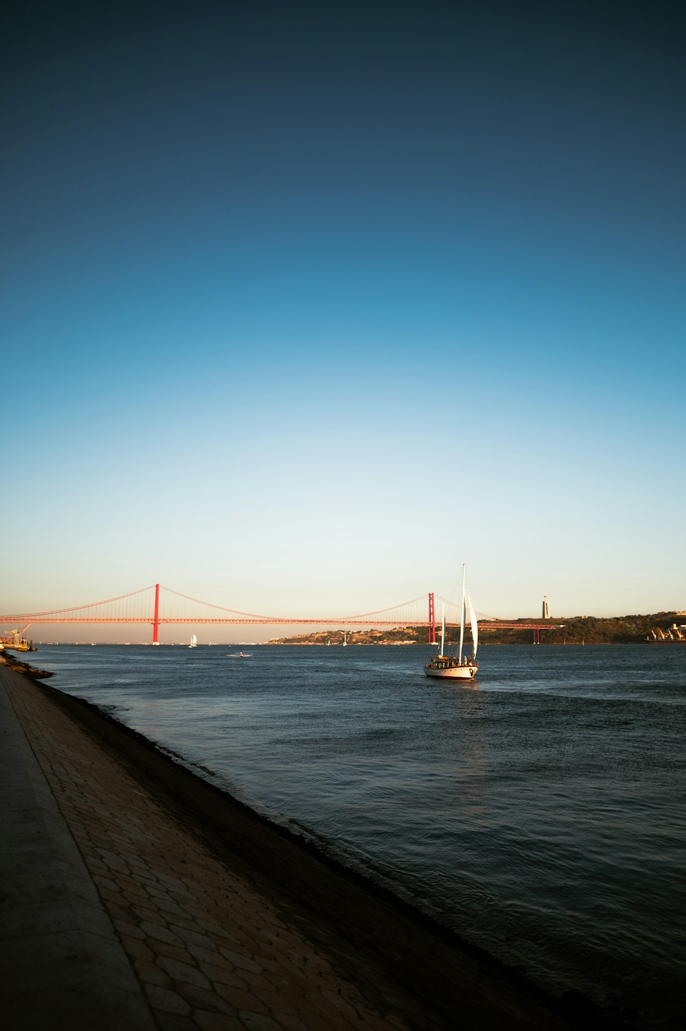 a sailboat in the water near a bridge