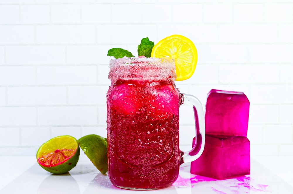 a pitcher filled with liquid next to a slice of fruit