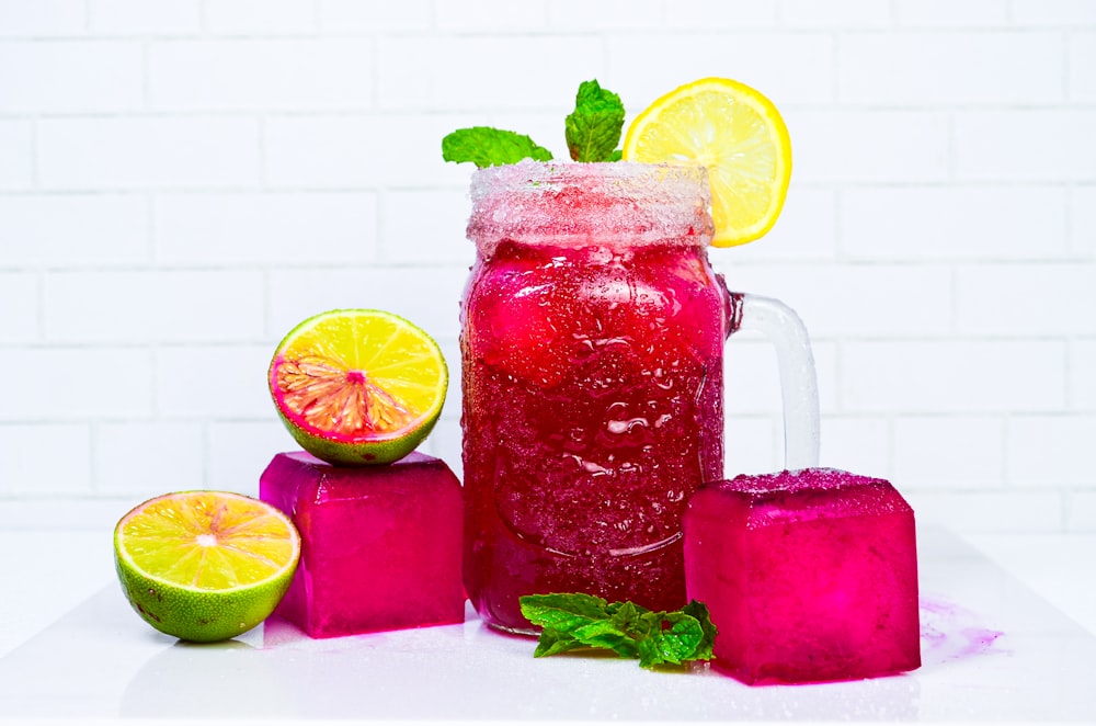 a pitcher filled with liquid next to sliced fruit