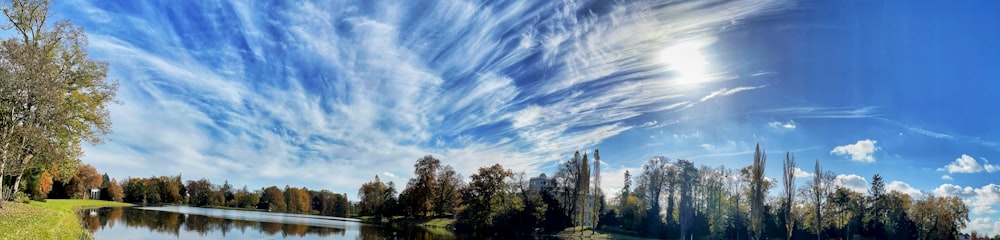 a lake surrounded by trees under a blue sky