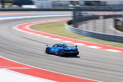 A sleek motorsports car speeding through a curve, motion blur emphasizing speed and precision on a dark racetrack.