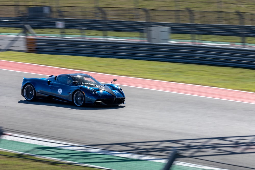 a blue sports car driving down a race track