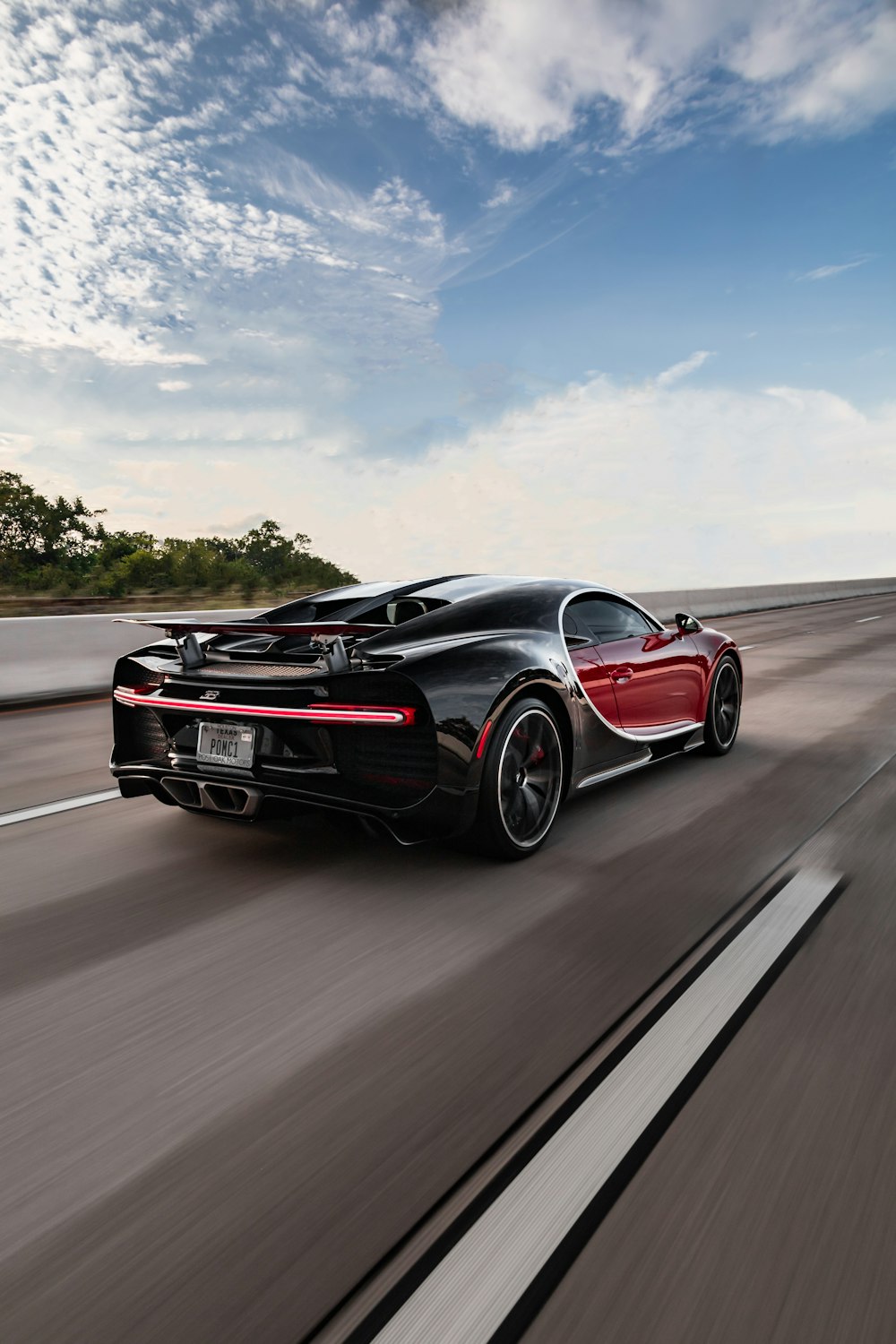 Un coche deportivo negro y rojo conduciendo por la carretera