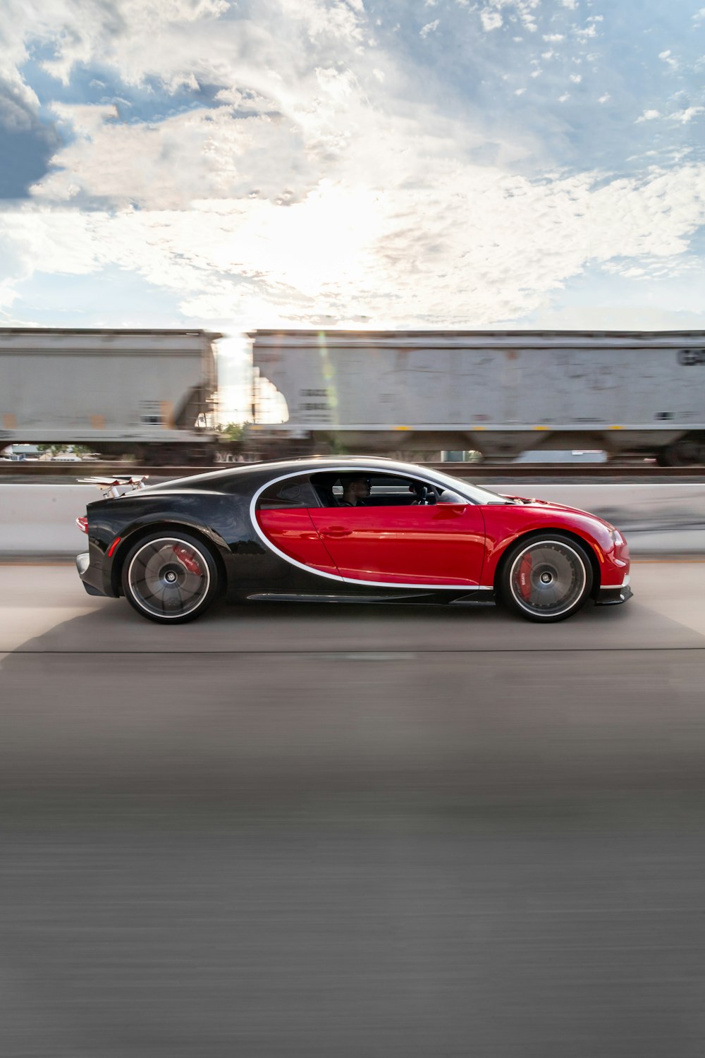 a red and black car driving down a street