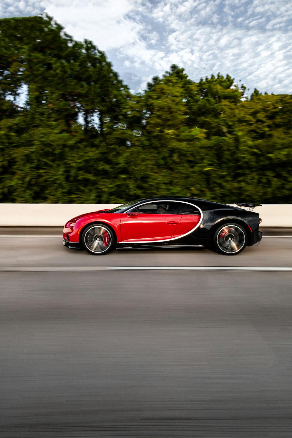 a red and black bugatti driving down the road