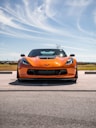 an orange sports car parked on the side of the road