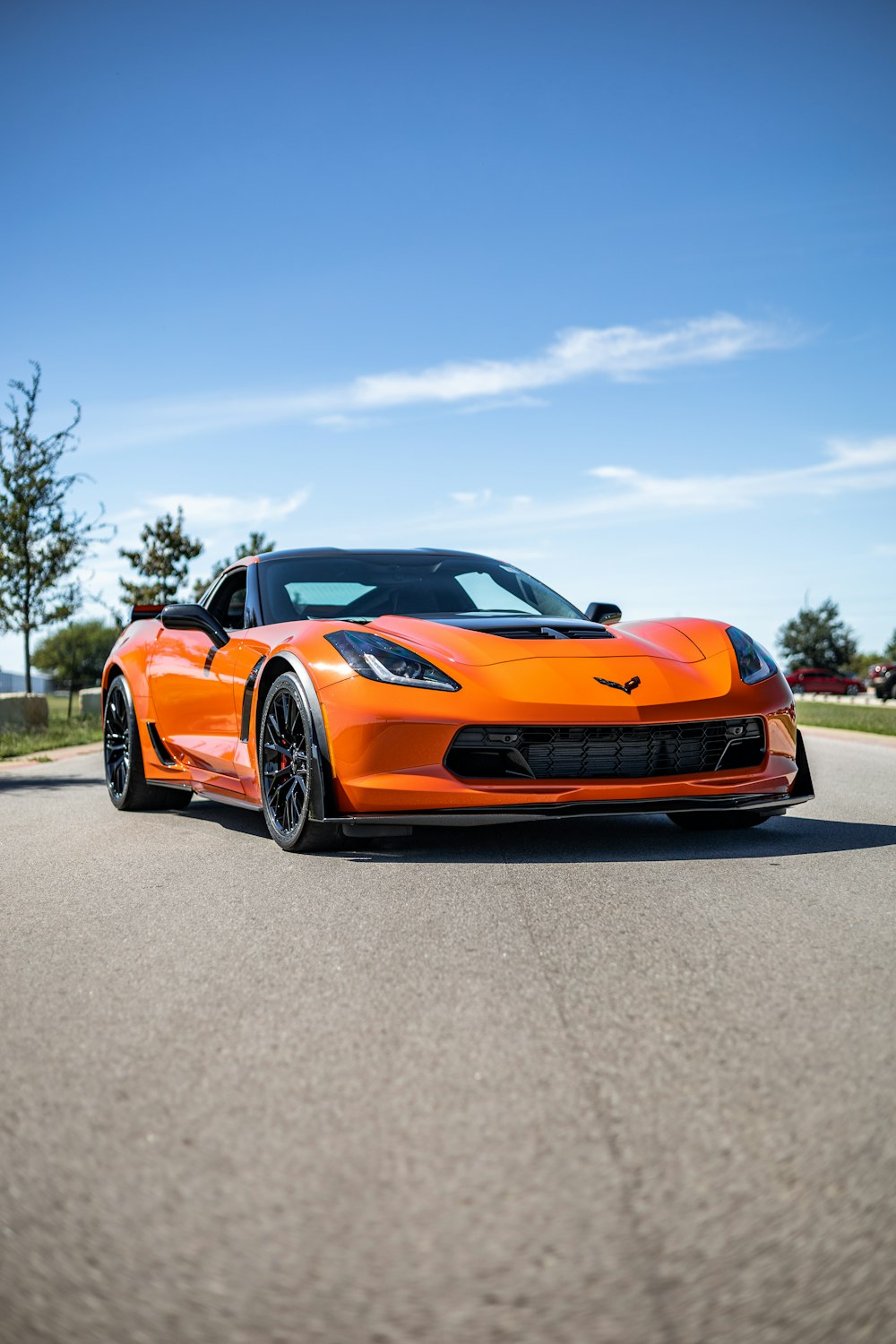 an orange sports car driving down a road