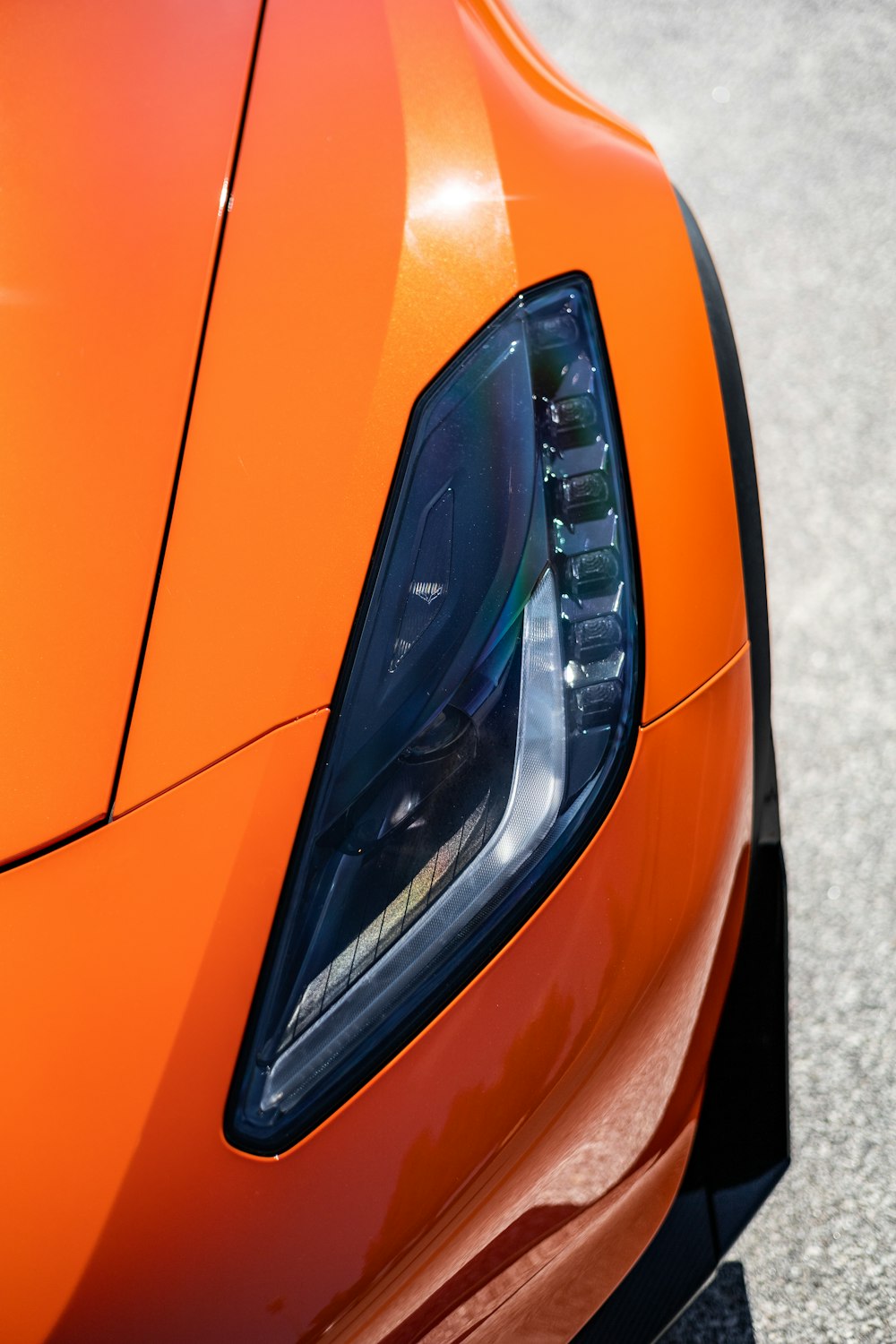 a close up of the headlight of an orange sports car