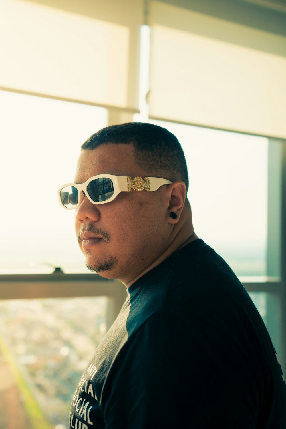 a man wearing sunglasses looking out a window