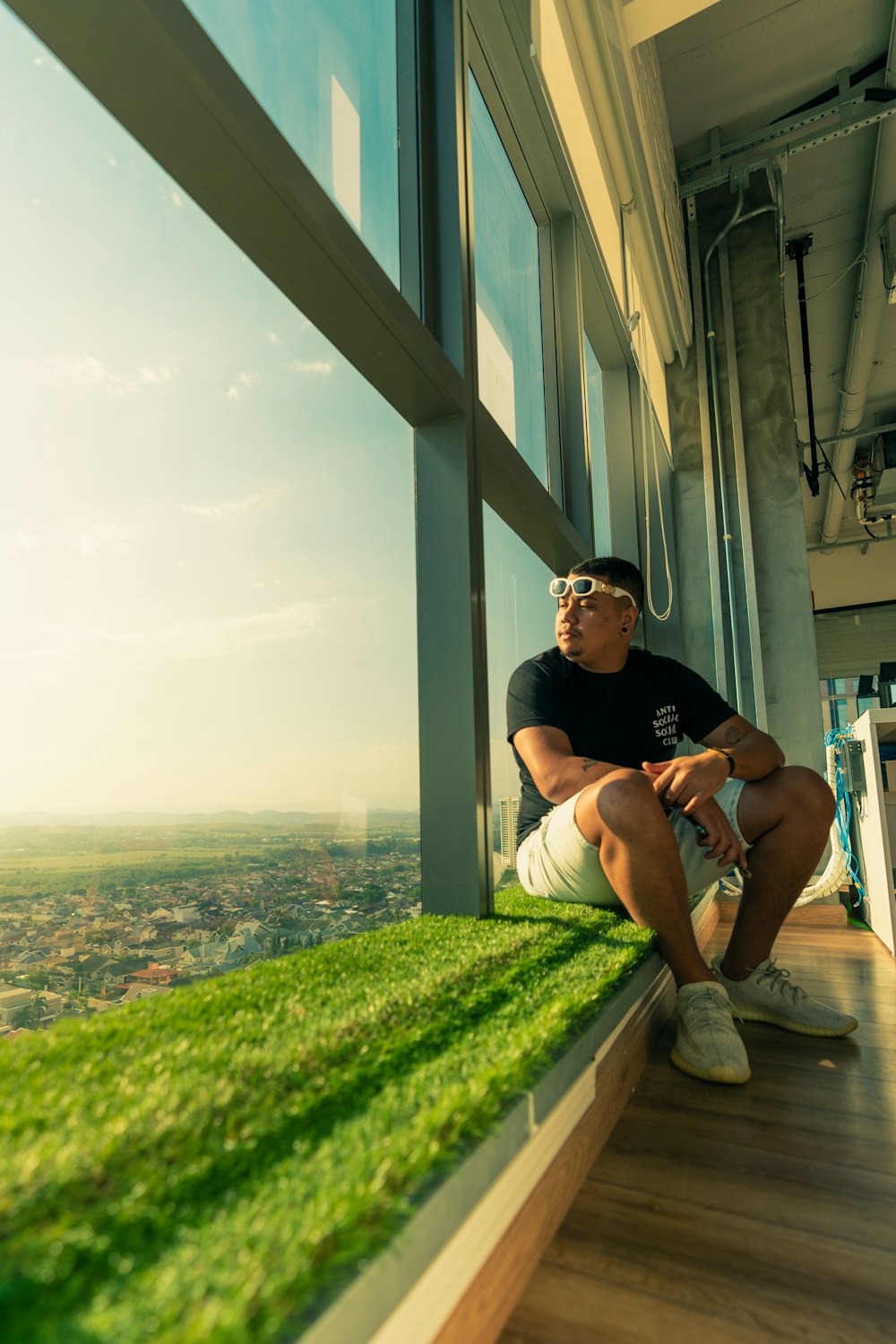 a man sitting on a window sill with a view of a city