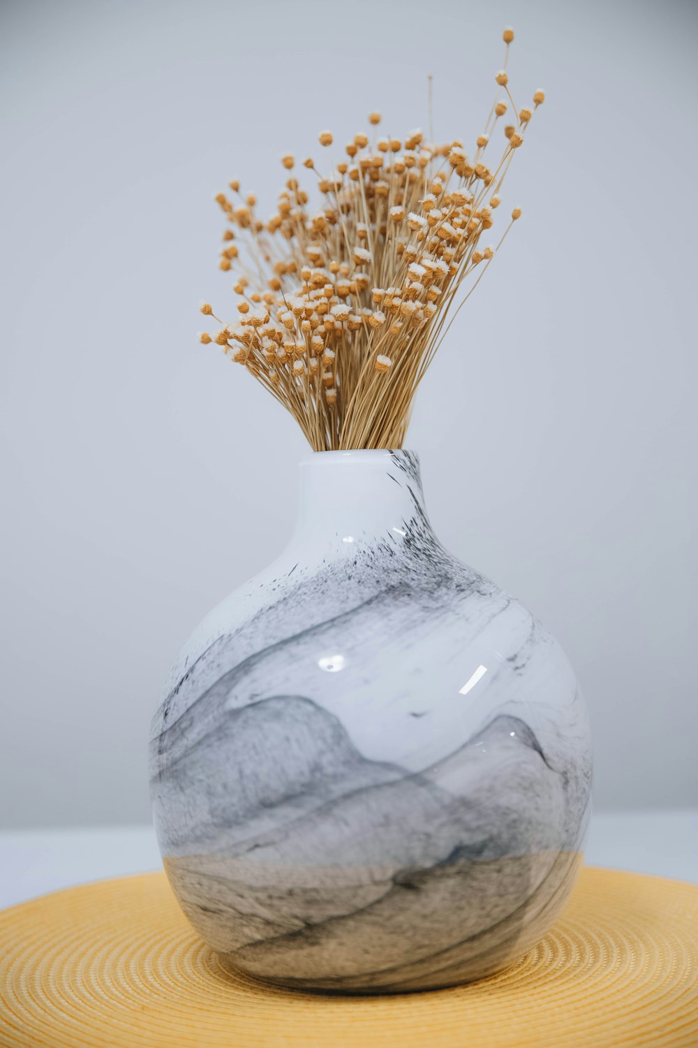 a white vase with a bunch of dried flowers in it