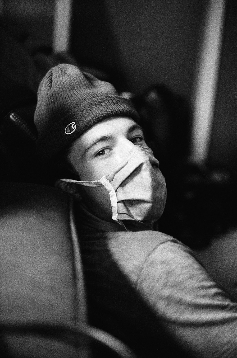 a young man wearing a mask and a beanie