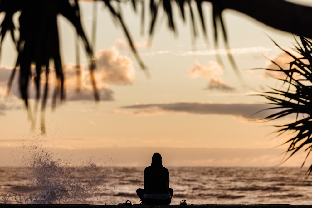 a person sitting on a bench in front of the ocean