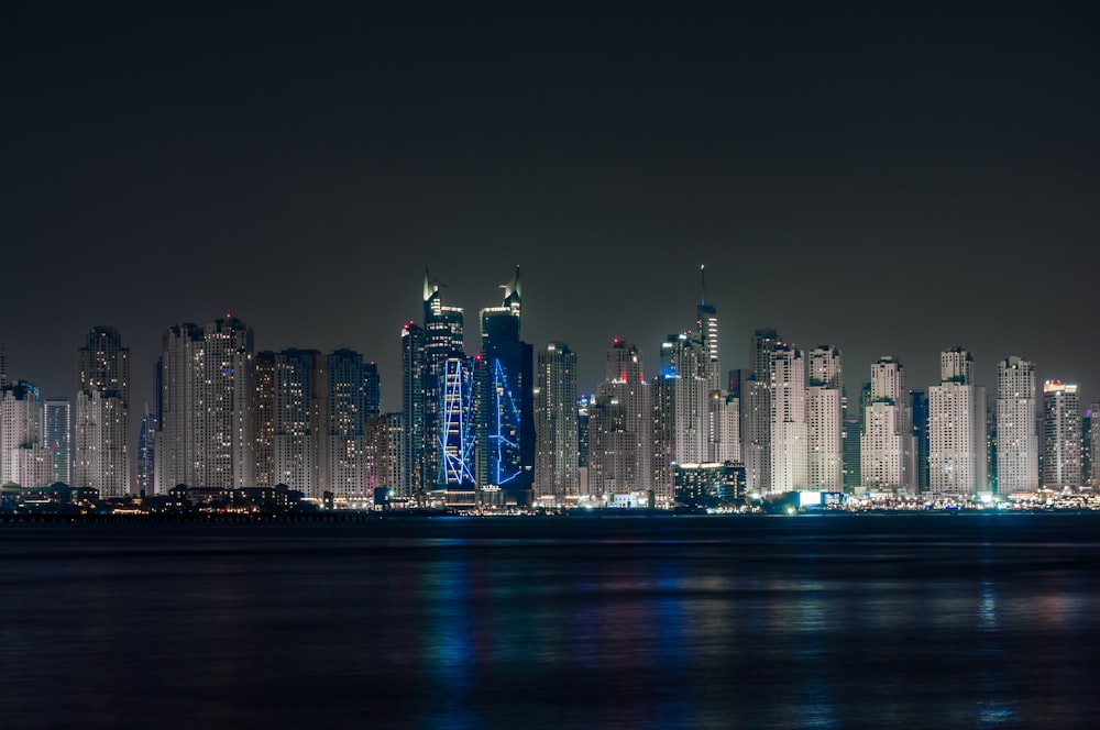 a city skyline at night with lights reflecting off the water