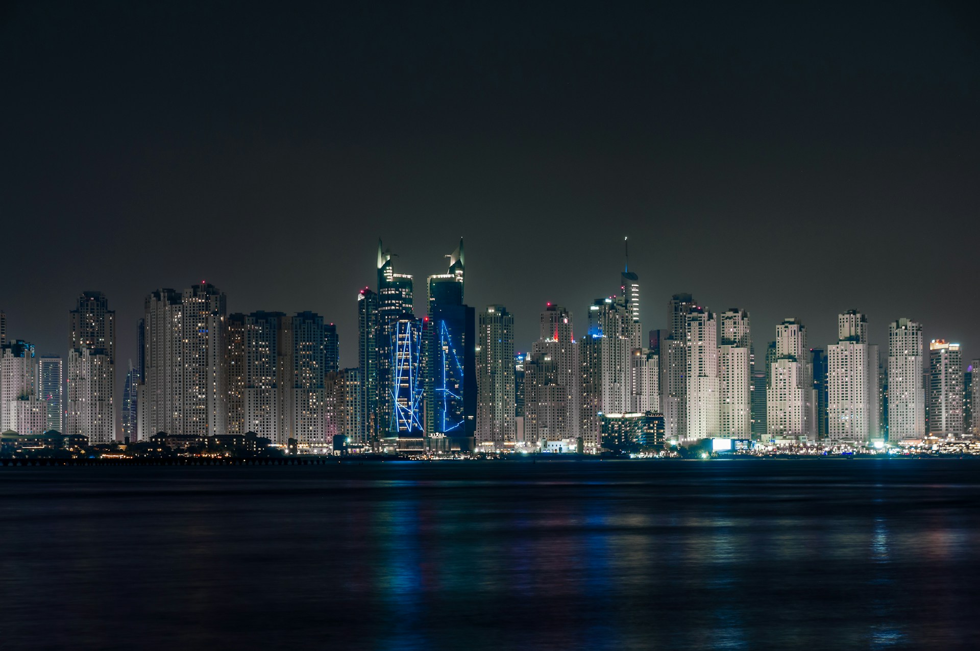 a city skyline at night with lights reflecting off the water