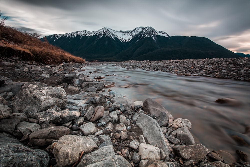 a rocky river with mountains in the background