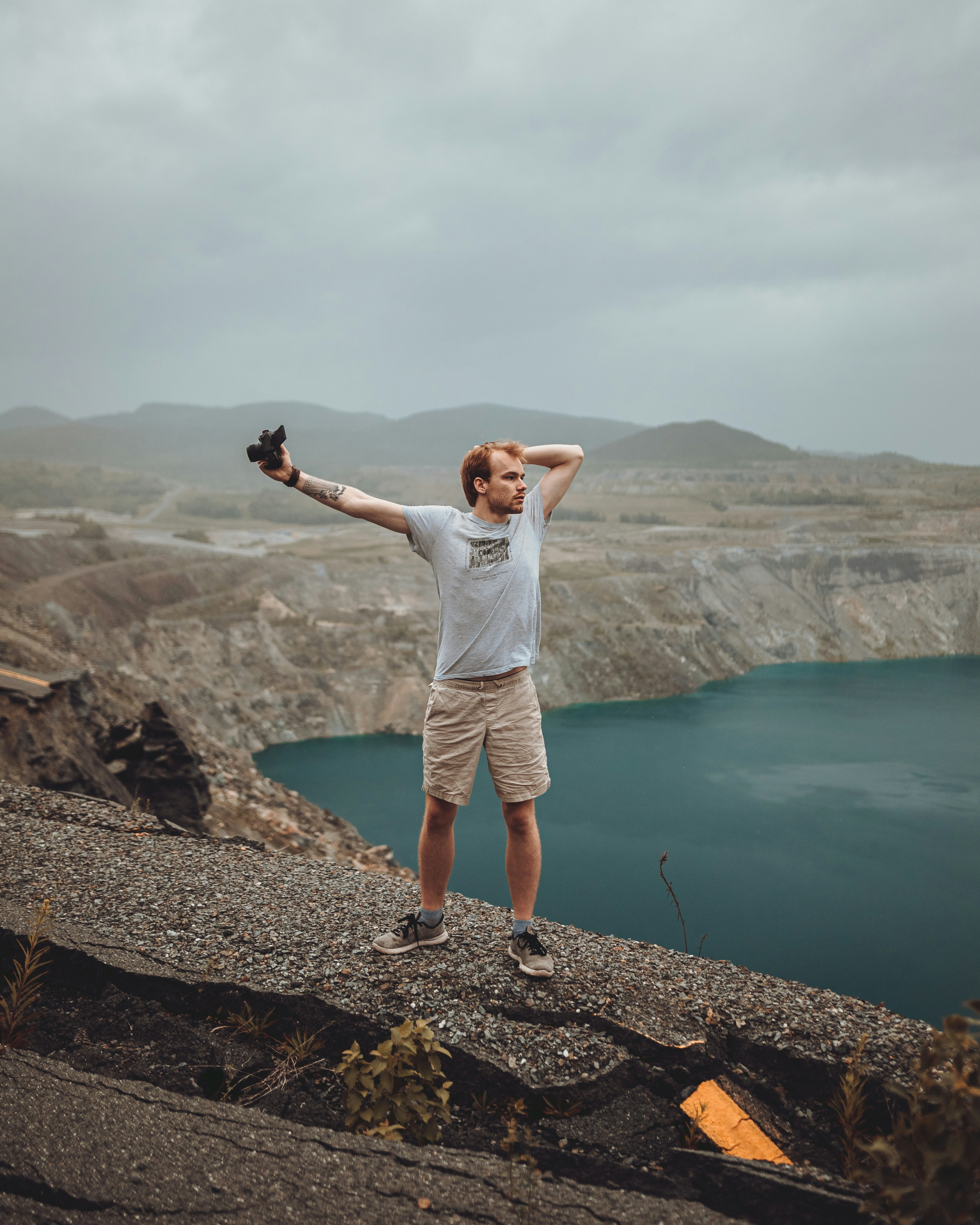 a man standing on top of a mountain next to a lake