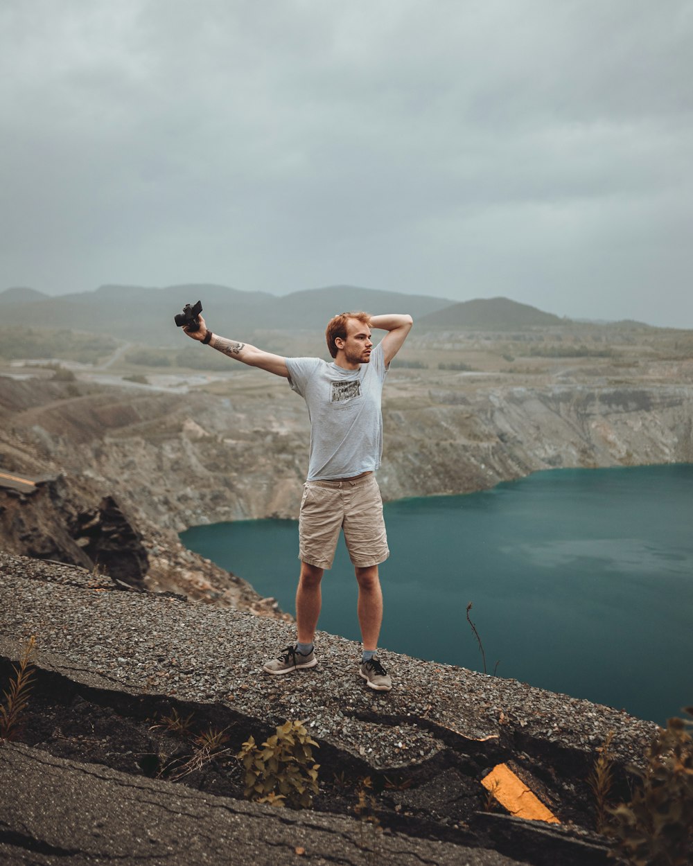 um homem de pé no topo de uma montanha ao lado de um lago