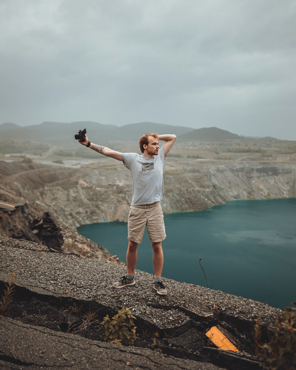 a man standing on top of a mountain next to a lake