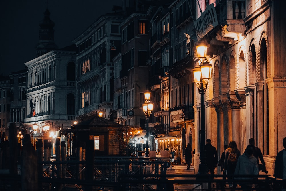 a group of people walking down a street at night