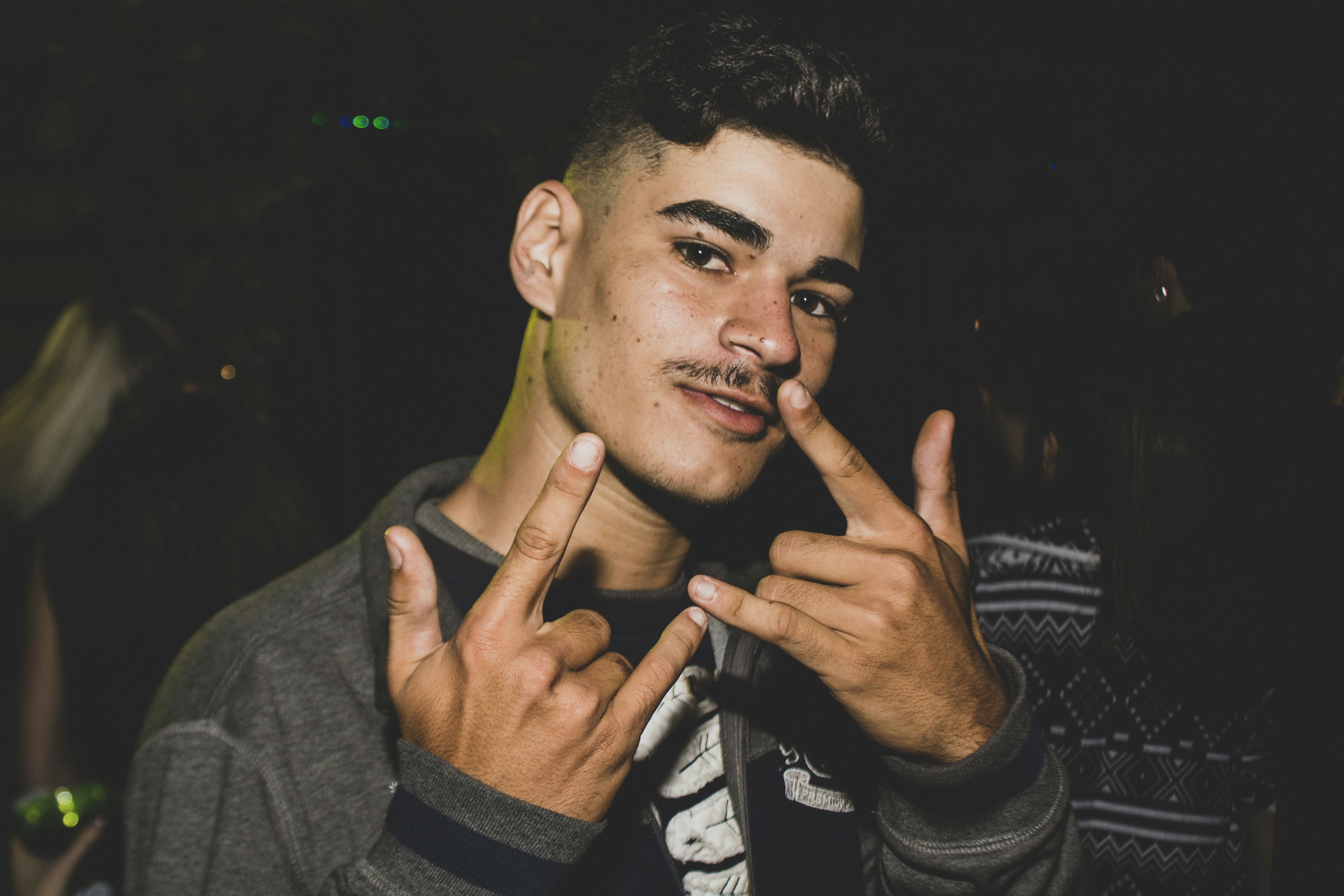 a man with a moustache making a peace sign