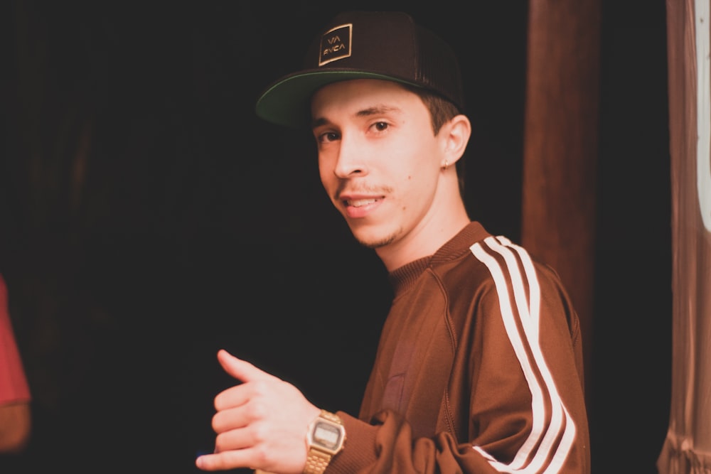 a young man wearing a baseball cap and a brown jacket