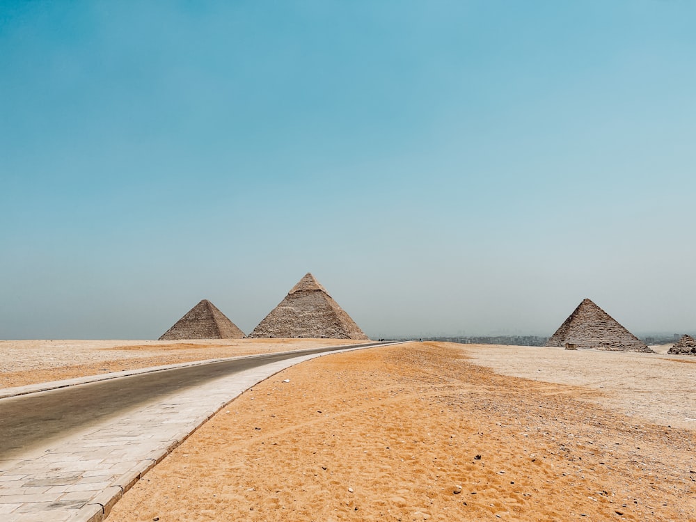three pyramids in the desert near a road