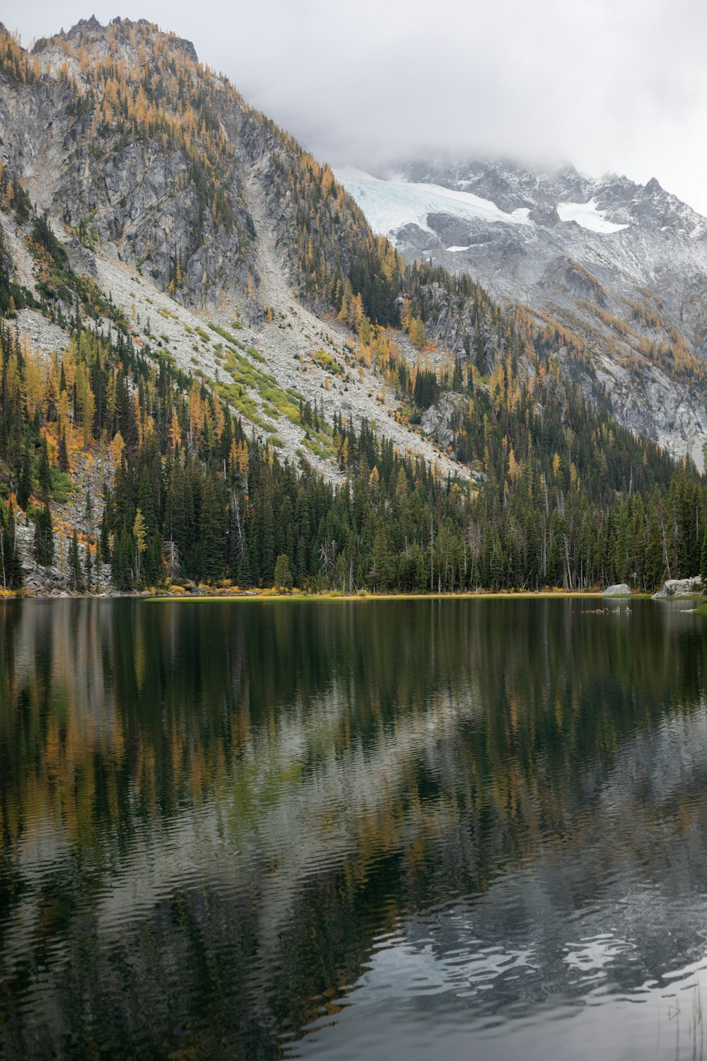 a mountain range with a lake surrounded by trees