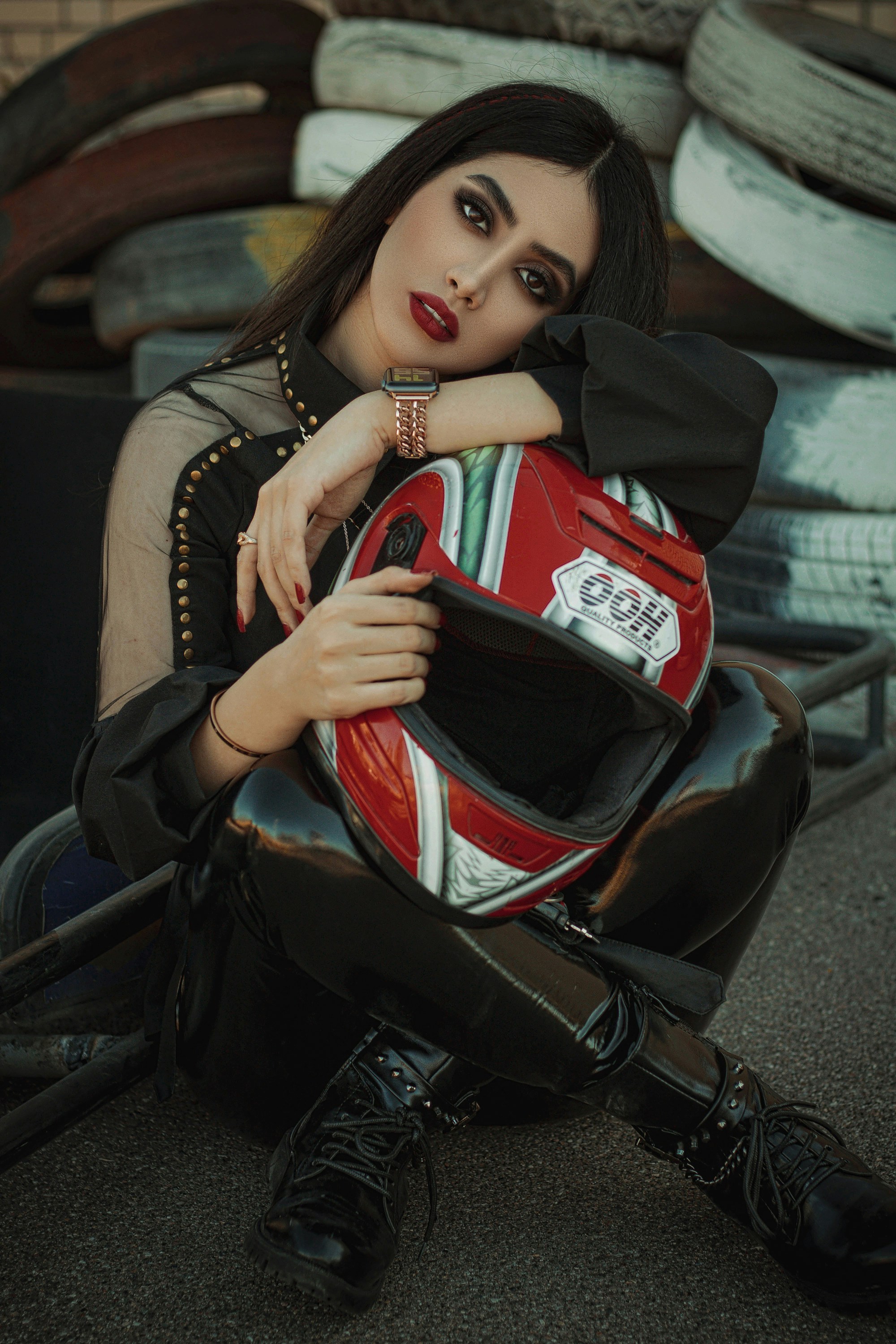 a woman sitting on the ground with a motorcycle helmet
