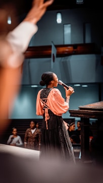a woman standing in front of a piano while holding a microphone
