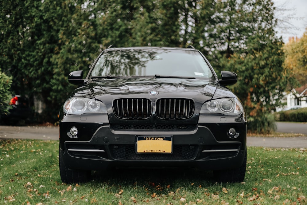 the front of a black bmw x5 parked in the grass