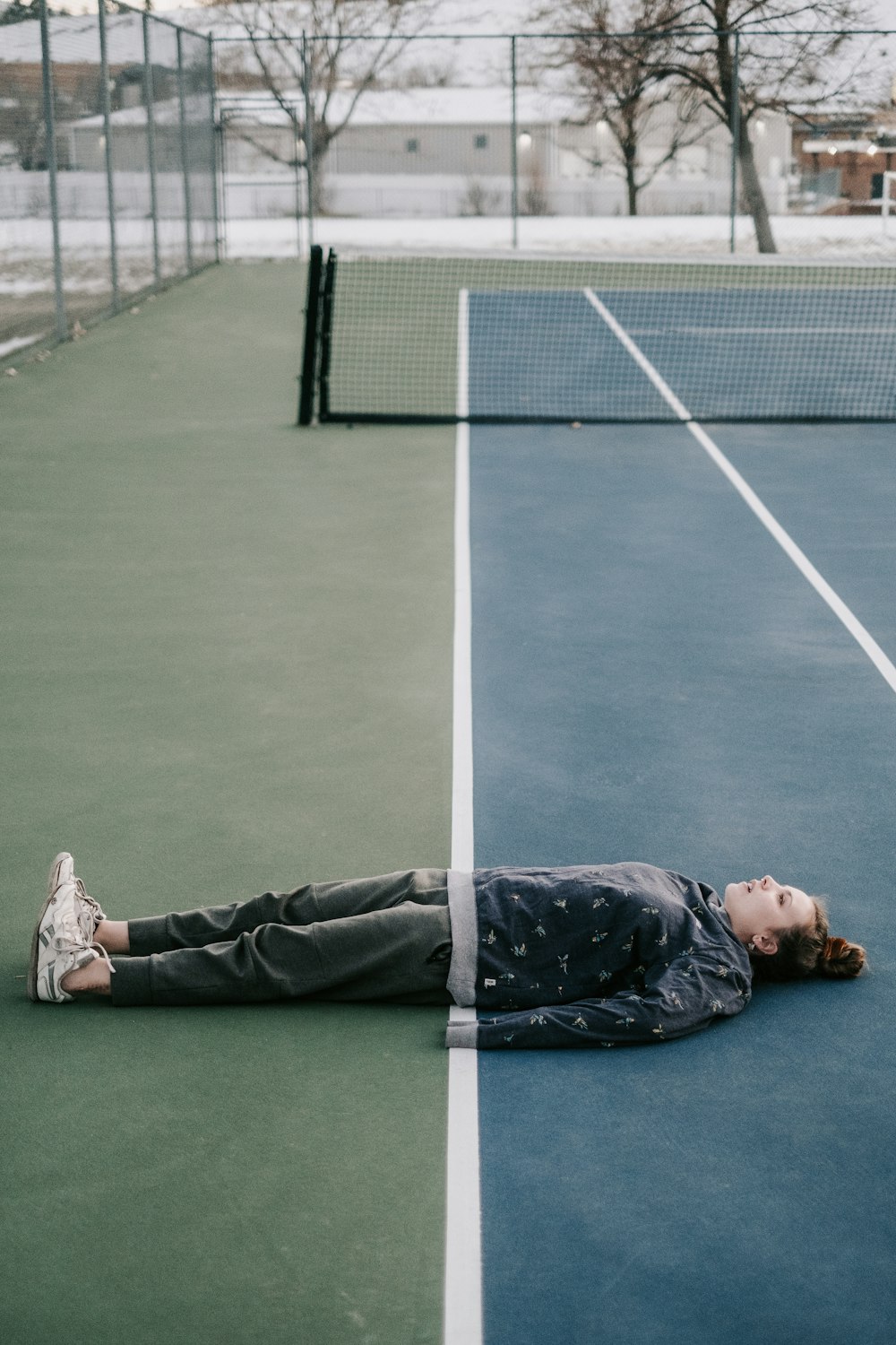 a person laying on the ground on a tennis court