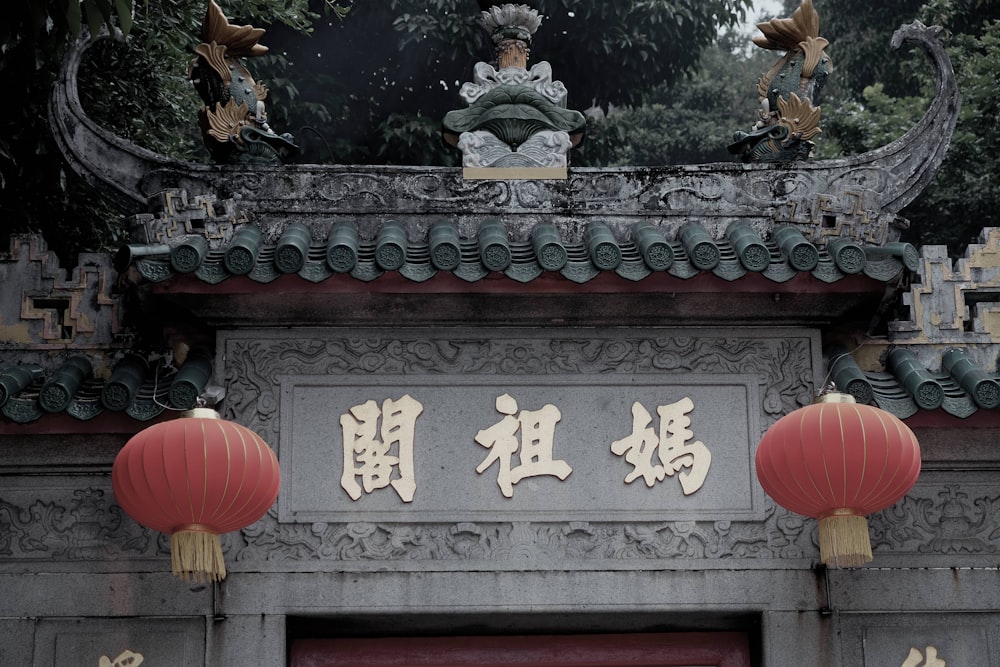 a chinese building with two red lanterns hanging from it's roof