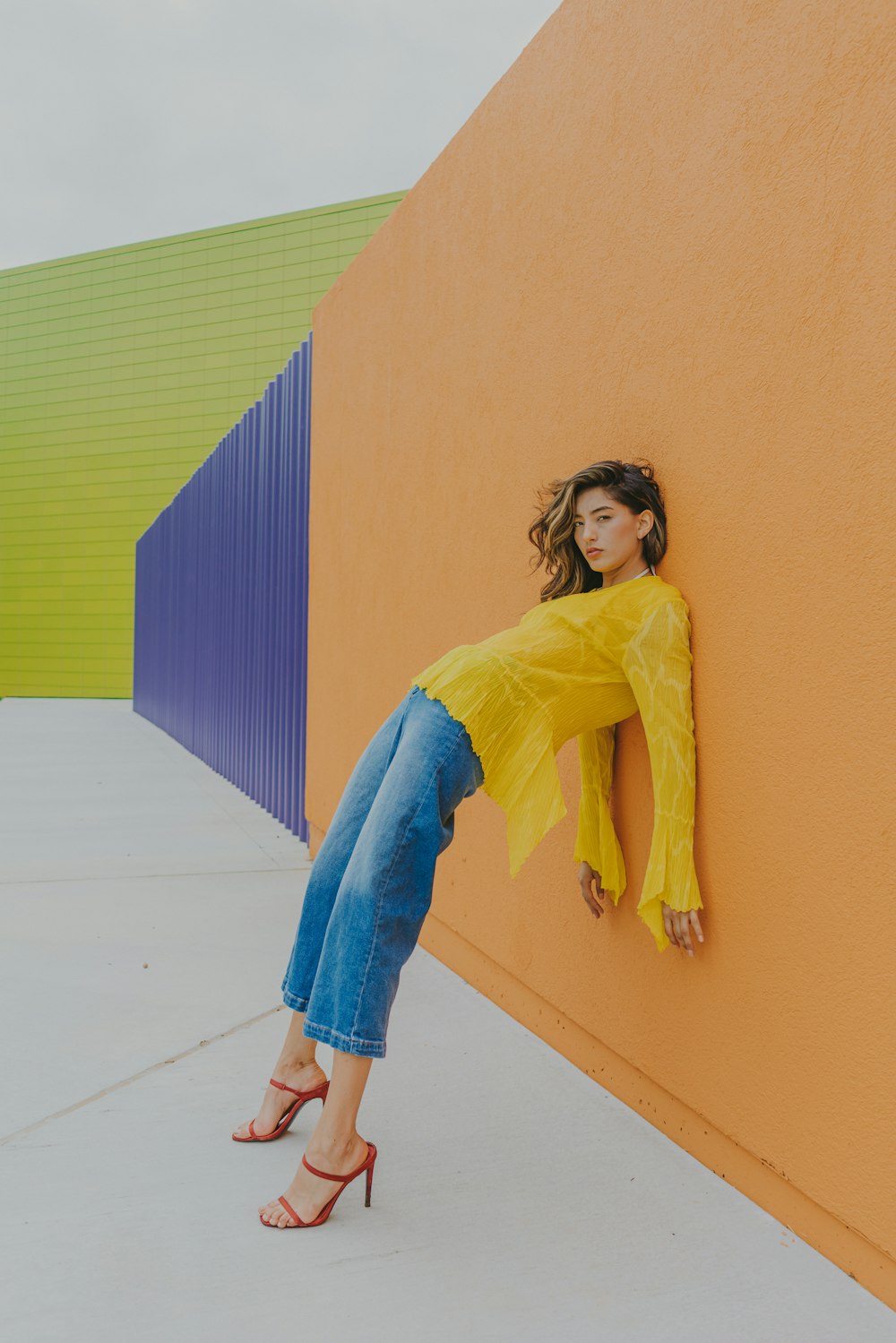 a woman leaning against a wall in a yellow top
