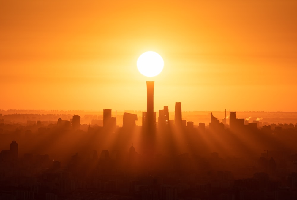 the sun is setting over a city with tall buildings