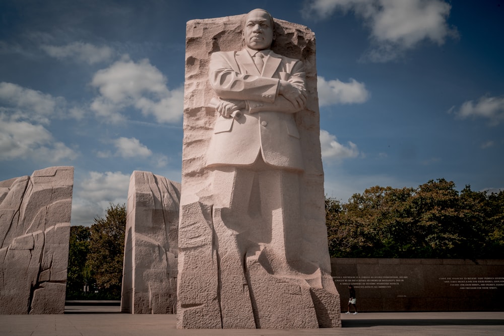 Una estatua de un hombre con los brazos cruzados junto a otra estatua de un hombre