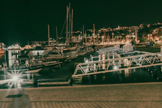 Evening view of a marina lit up with warm lights reflecting on the calm sea.