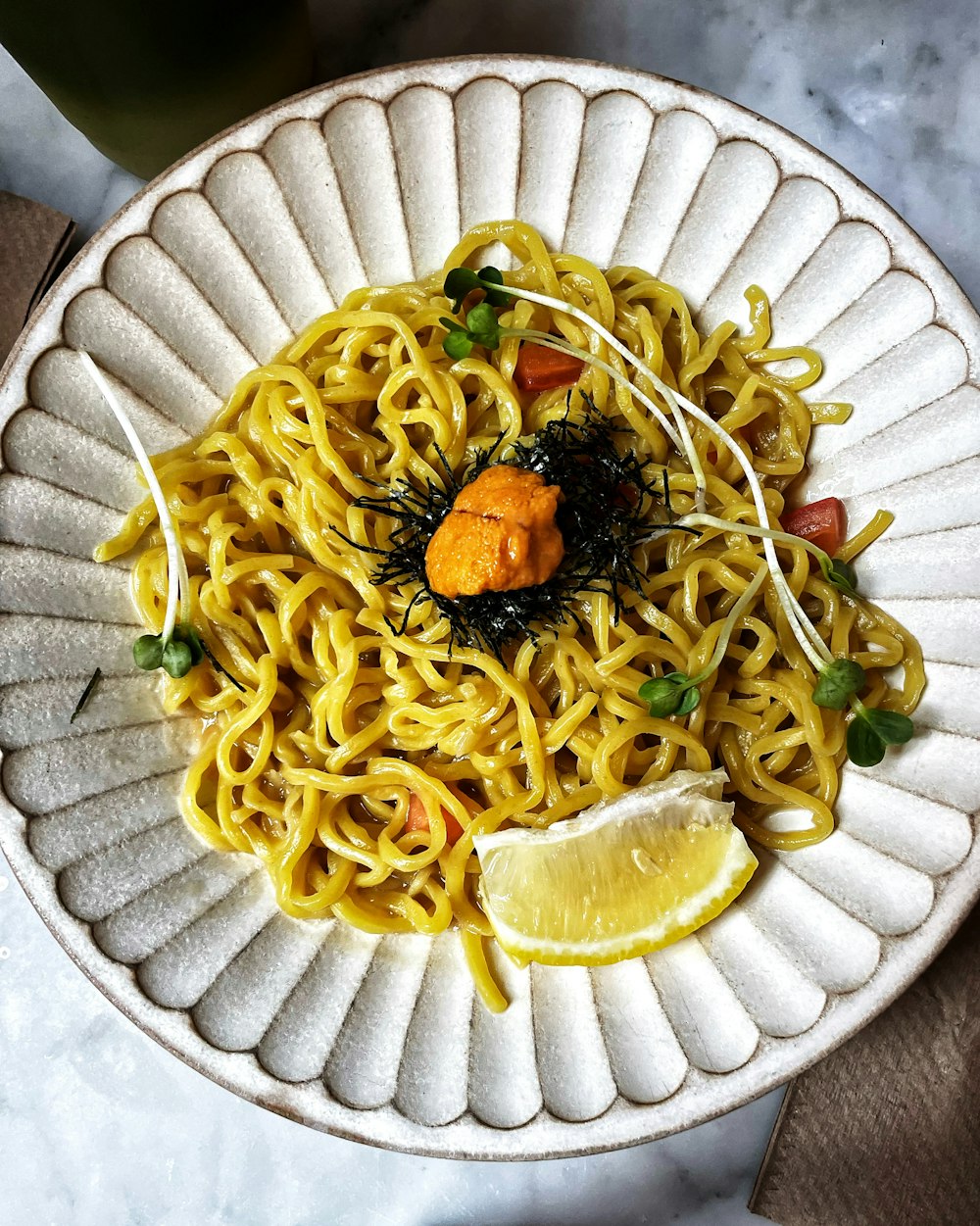 a white plate topped with noodles and a lemon wedge