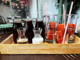 A vibrant spread of colorful juice bottles and tea glasses arranged elegantly on a wooden table with fresh herbs and spices.